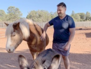 Man smiling while petting a horse